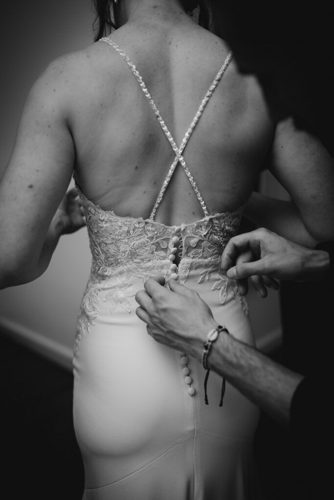 Préparatif de la mariée avec les boutons dans le dos de la robe