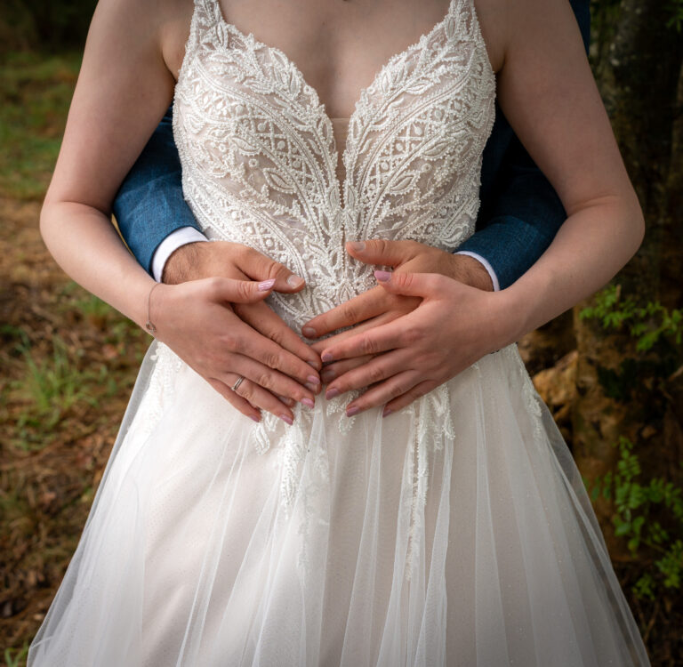 Cœur avec les mains sur la robe de la mariée