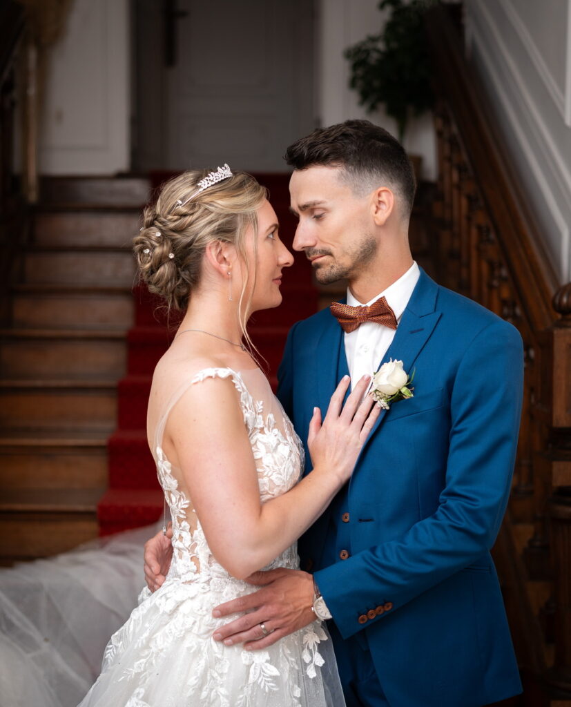 Les mariés se regardent enlacés au pied du grand escalier du Manoir - Photographe mariage Yvelines