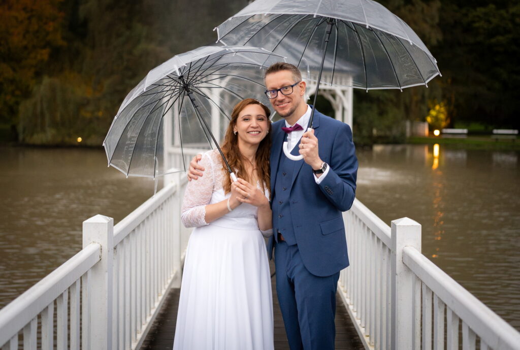 Les mariés sous des parapluies pour les photos au Domaine des Fontenelles