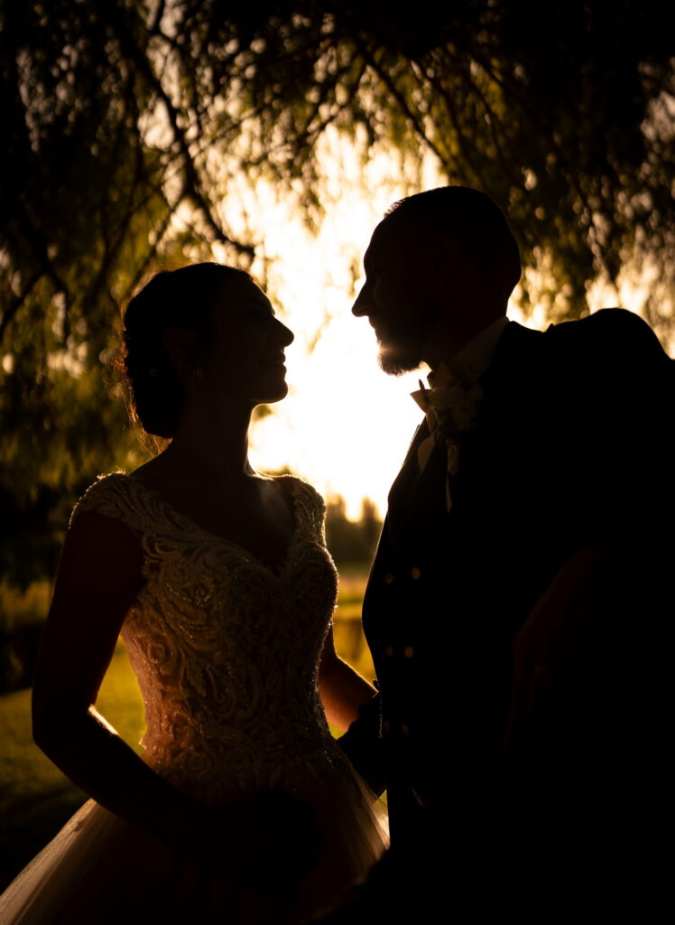 Mariés en contre jour se regardant sous un arbre - photographe mariage Val-d'Oise