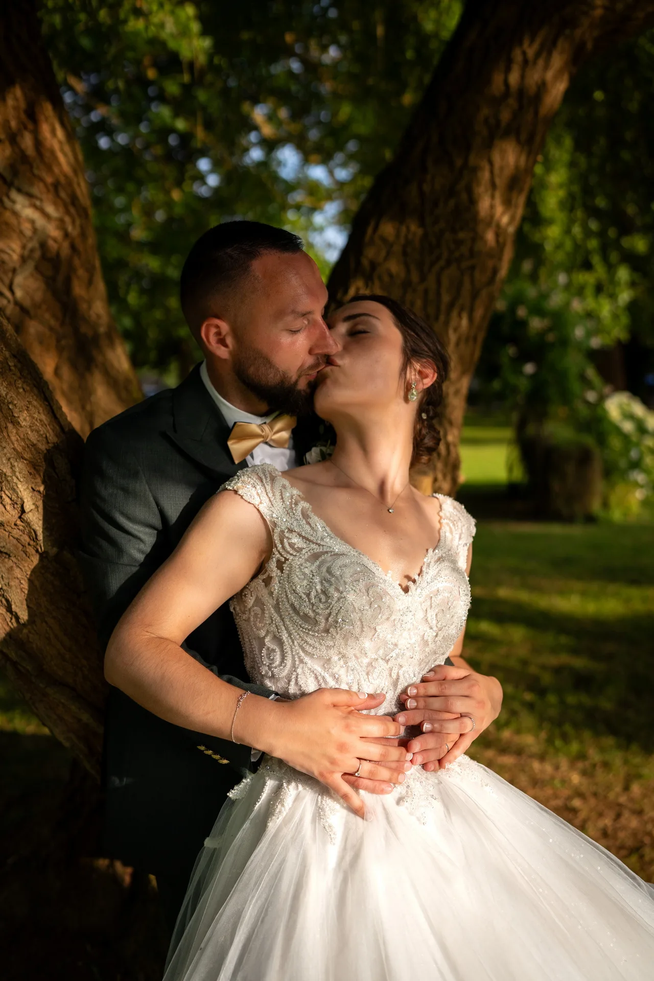 Mariés s'embrassant sous un arbre au soleil couchant, photographe mariage Yvelines